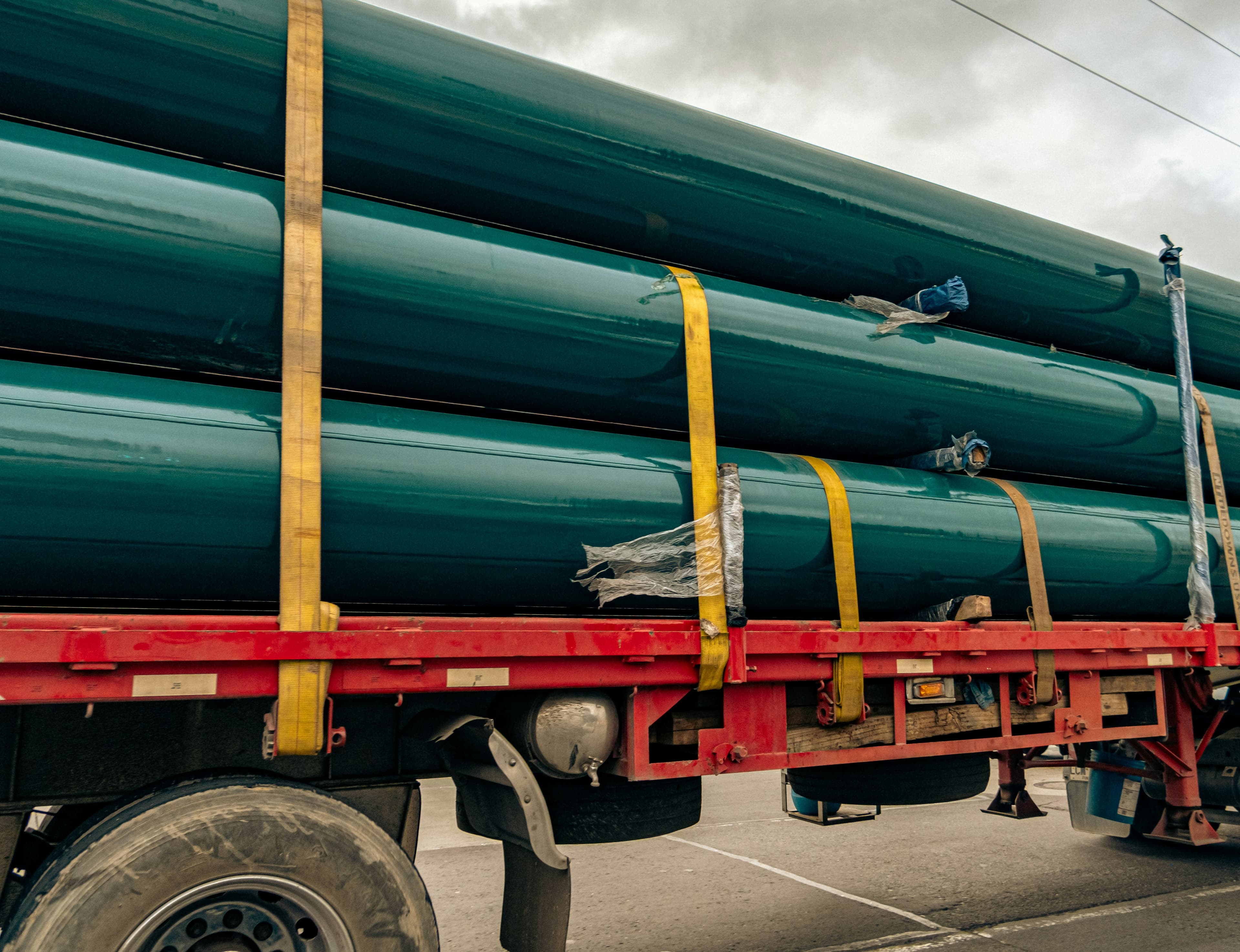 Coated steel pipe strapped down on a flatbed trailer