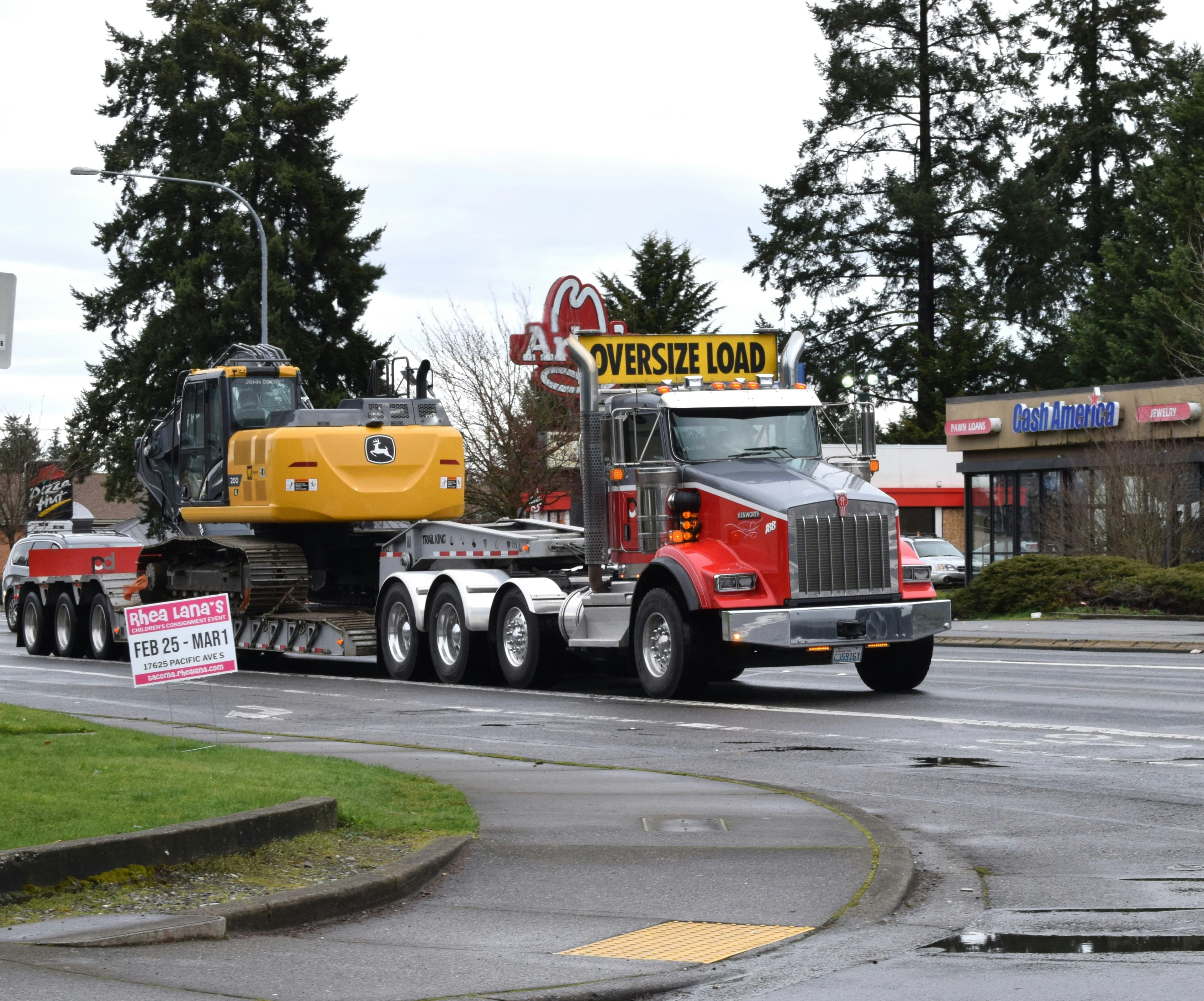 Kenworth with an oversize load banner hauling an excavator on a multi-axle trailer